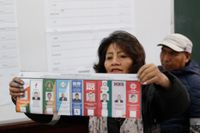 En vallokalsarbetare i La Paz, Bolivia, håller upp en röstsedel med ett kryss för den sittande presidenten Evo Morales.