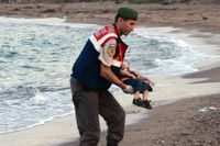 En polis bär upp Alan Kurdis livlösa kropp på stranden i Kos, Grekland, i september i år.
