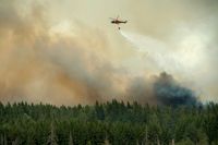En helikopter vattenbombar skogsbranden i Västmanland, då 14 000 hektar skog till ett värde av hundratals miljoner brann upp sommaren 2014. Arkivbild.