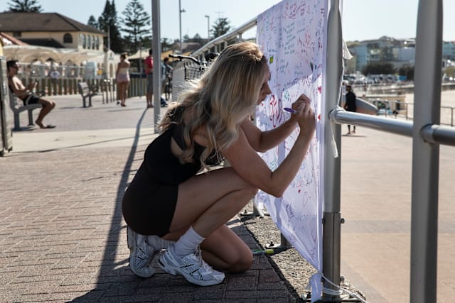 Jesse Clark writes a message for the victims of the Bondi Beach terror attack.