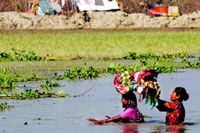 Nyligen svepte cyklonen Sidr in över kuststräckorna i Bangladesh. Flera hundra dog. Många byar utplånades och tusentals människor blev hemlösa. Här är det två kvinnor som hämtat skänkta förnödenheter och vadar hemåt genom ett översvämmat område i Southkali i distriktet Bagerhat.