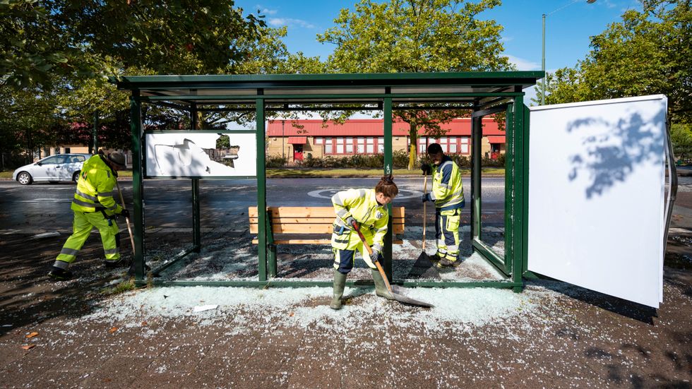 Personal från Malmö stad röjer upp krossat glas från en krossad busskur i Rosengård i Malmö.