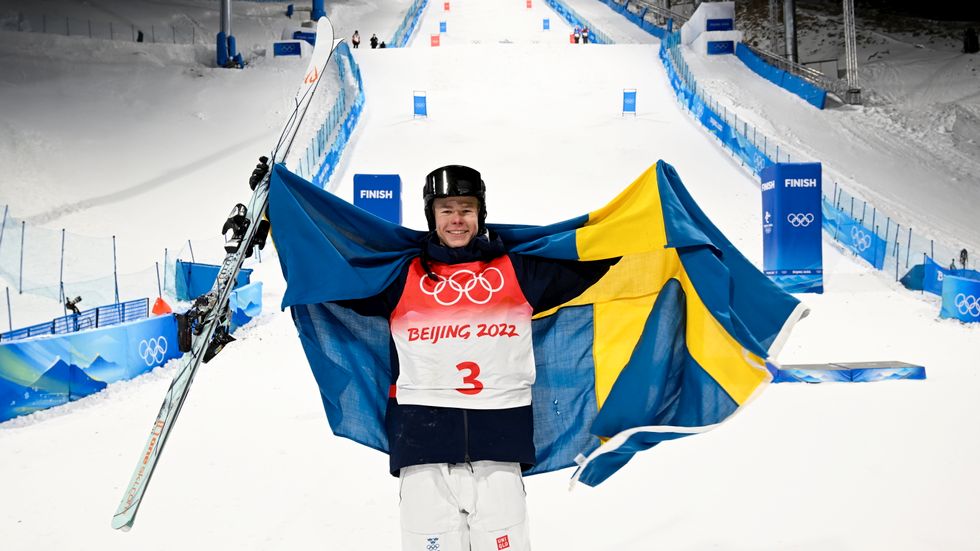 Walter Wallberg jublar med den svenska flaggan efter att han tagit OS-guld i herrarnas puckelpist under vinter-OS i Peking 2022.