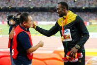 Usain Bolt mottar ett vänskapsband av kameramannen Song Tao.
