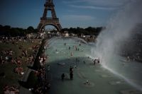 Här svalkar människor sig i fontänerna framför Eiffeltornet i Paris.