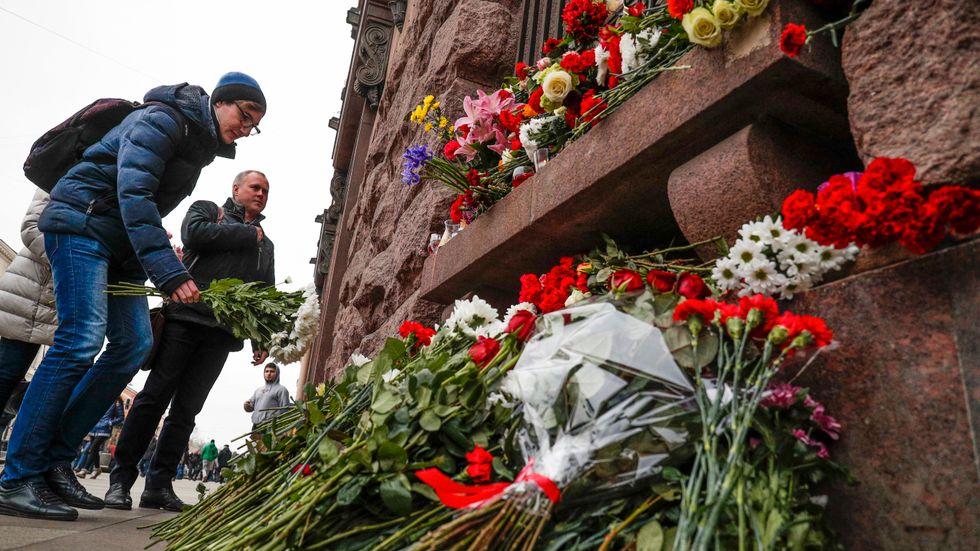 En man lägger ner blommor vid en minnesplats för offren för dådet i S:t Petersburgs tunnelbana.