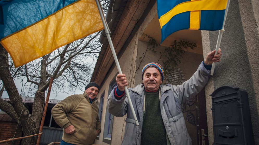 Ukraina Oleksandr Zabloda, byns läkare, viftar med en ukrainsk och en svensk flagga vid SvD:s besök i november 2022.