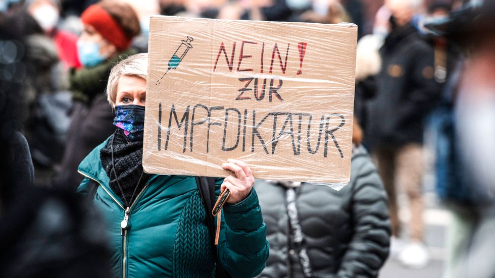 En person med skylten: ”Nej till vaccindiktatur” deltar i en demonstration mot de tyska restriktionerna.