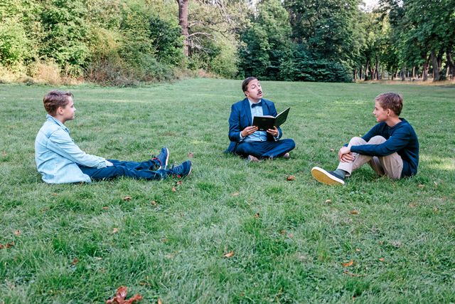Lässtund i parken för Oskar och Jakob. David läser en sida där alla R bytts ut till U – roligt tycker killarna. 