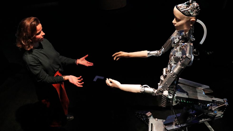 En kvinna interagerar med en robot på en AI-mässa i London. 