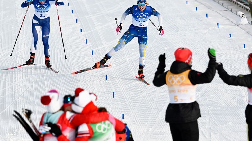 Jonna Sundling, i mitten, fixar ett stafettbrons till Sverige efter att ha spurtat ner Finlands Krista Pärmäkoski, till vänster. I framkant firar det ryska laget OS-guldet medan tyskorna till höger jublar åt silver.