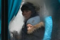 En kvinna och hennes barn på en buss i färd att lämna Luhansk i östra Ukraina, efter Rysslands attack på torsdagen.
