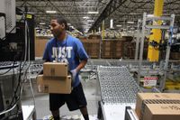 En anställd på ett Amazonlager i Kalifornien, USA, bär lådor. Personen har inget med artikeln att göra.