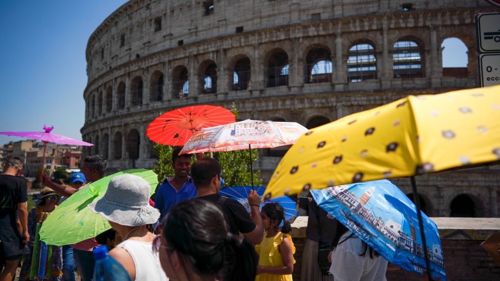 Människor söker svalka under paraplyer i Rom sommaren 2019. Arkivbild.