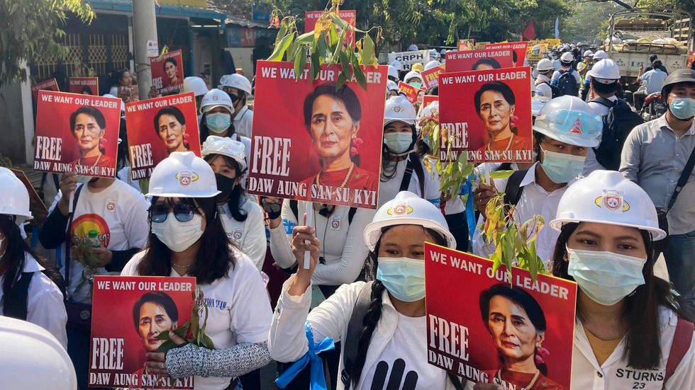Demonstranter håller upp bilder av den avsatta cila ledaren Aung San Suu Kyi vid fredagens protester i Mandalay.