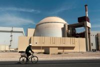 En man cyklar förbi en kärnkraftreaktor utanför staden Bushehr i Iran. Arkivbild.