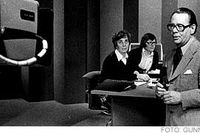 SVT:s nyhetsankare Lars Orup agerar framför TV-kameran med en expertpanel bakom sig i sveriges tlevisions TV-studio vid valvakan 1976.