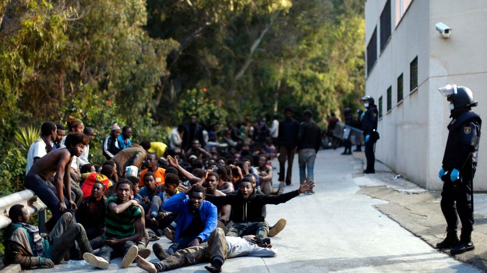 Migranter bevakas av spansk polis efter gränsstormningen i förra veckan.