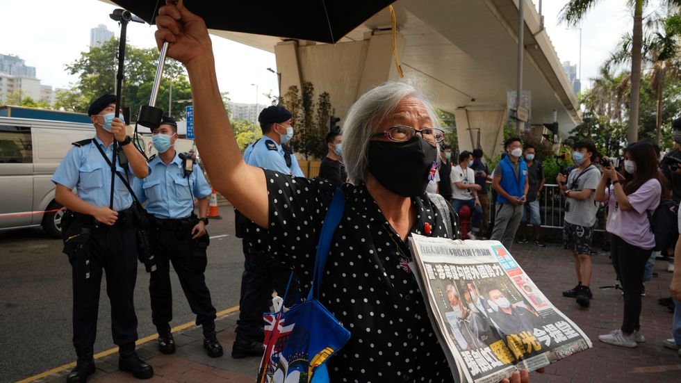 En demokratiaktivist med ett exemplar av Apple Daily utanför en domstol i Hongkong.