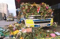 En polisbil täckt av blommor på Drottninggatan i närehen av platsen där lasbilen i fredags körde in i varuhuset Åhlens.