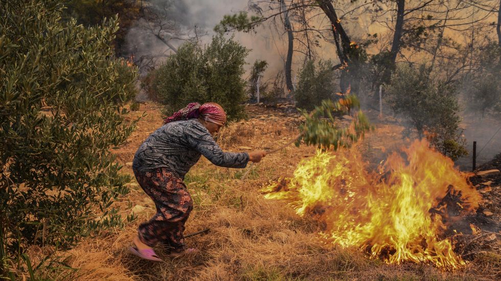 En kvinna försöker hindra eldens framfart nära Antalya.