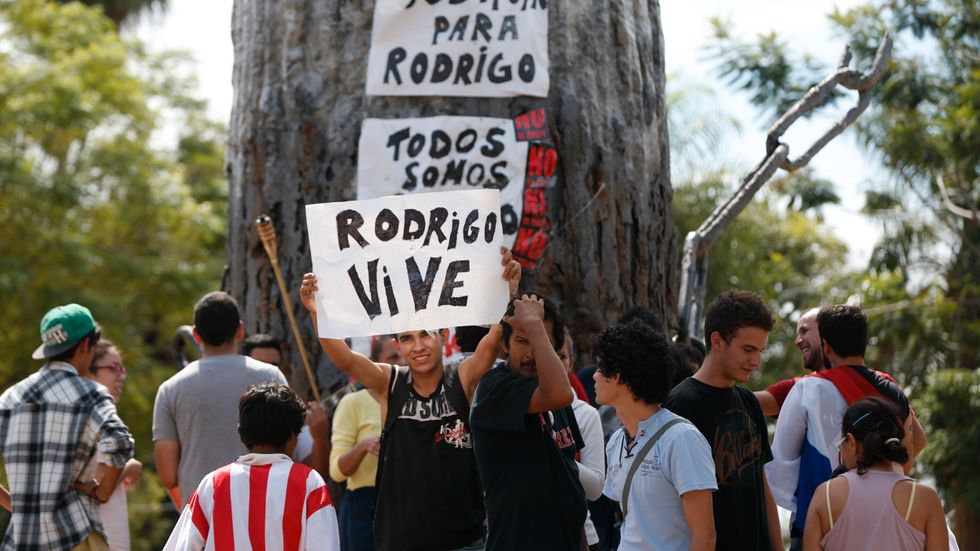 En man håller upp en skylt för att hedra den 25-årige man som dödades vid oroligheterna vid parlamentet i Paraguay.