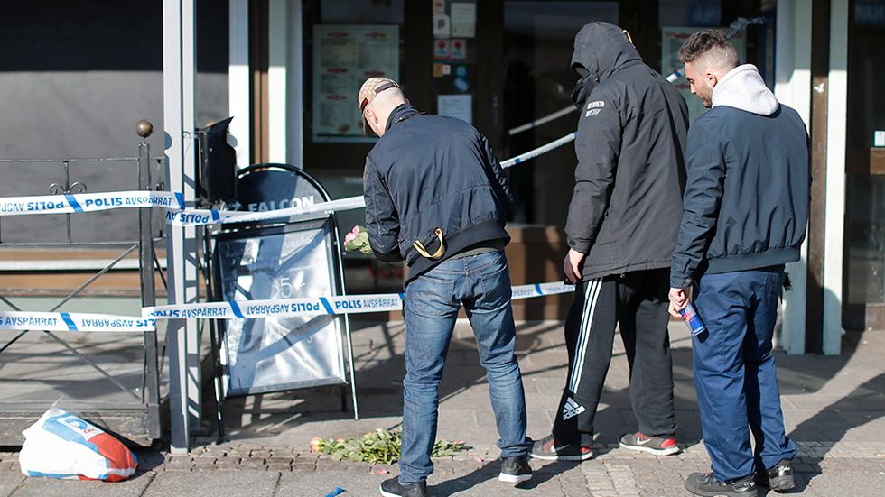 Blommor läggs vid  polisens avspärrningar på Vårväderstorget i Göteborg efter onsdagens skottlossning.
