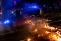 En polisbil kör över brinnande barrikader i Barcelona under natten till fredagen.