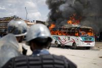 Poliser framför en buss som satts i brand i Katmandu.