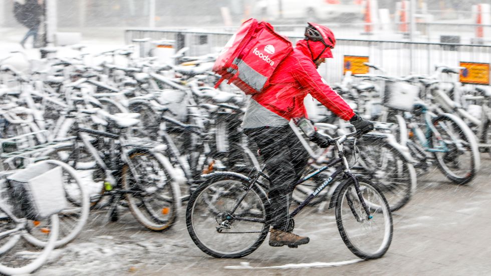 Ett cykelbud från Foodora tar sig fram i snöyran i centrala Stockholm.