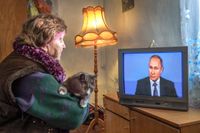 En rysk kvinna lyssnar på Vladimir Putins tal i tv.