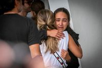 Två kvinnor tröstar varandra vid en samlingsplats för familj och vänner till de saknade.
