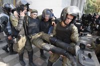 Polismän tar hand om skadad kollega efter granatattacken utanför Ukrainas parlament i Kiev.