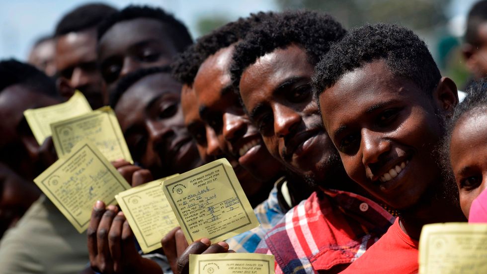 Väljare i Hawassa visar upp sina identitetshandlingar medan de köar, i samband med att vallokalerna öppnade i onsdags.