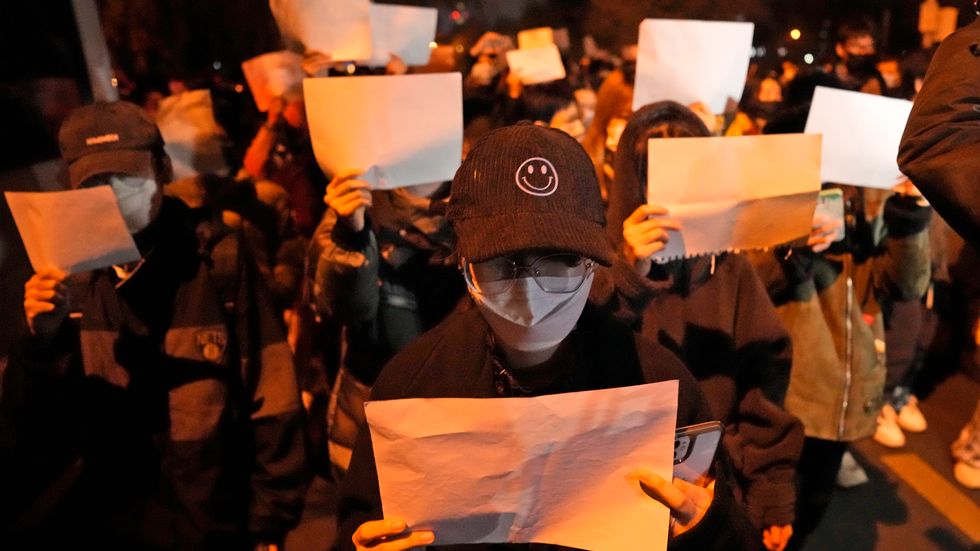 Demonstranter håller upp vita pappersark, som ska symbolisera censur, under en demonstration i Peking på söndagen.