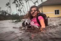 Freeportbon Julia Aylen och hennes hund evakuerar sitt översvämmade hem på ön Grand Bahama i norra Bahamas.