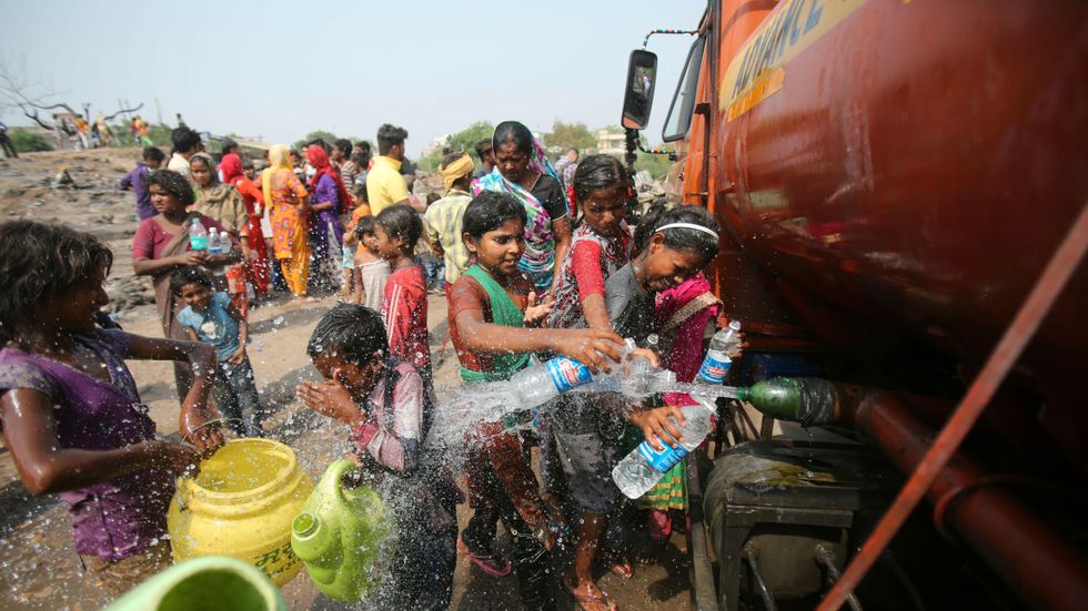 Människor fyller sina vattenflaskor vid en tank i Jammu, Indien.