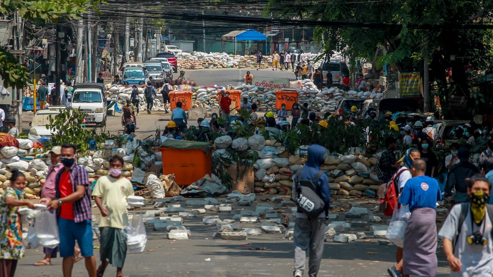 Demonstranter samlas längs en väg som blockerats för att hindra säkerhetsstyrkornas framfart i Myanmars största stad Rangoon på tisdagen.
