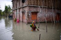 Invånare i byn Pratap Nagar i Bangladesh vadar genom vattenmassor för att ta sig till sina hem. Översvämningar blir vanligare i klimatförändringarnas spår. Arkivbild.
