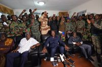 Revolterande soldater står samlade bakom Elfenbenskustens försvarsminister Alain-Richard Donwahi (i mitten längst fram) strax innan han tvingades kvar i byggnaden.