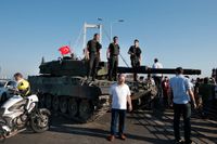 Polis och civila står runt en stridsvagn i Istanbul.