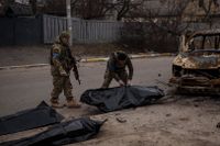 Ukrainska soldater tar om hand kropparna efter fyra dödade civila ur en förkolnad bil i staden Butja utanför Kiev. Bild från den 5 april.