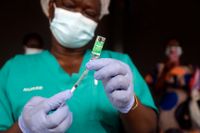 En sjuksköterska i Nigeria förbereder dos coronavaccin. WHO varnar nu för att den afrikanska kontinenten riskerar att drabbas av en ny covidvåg på grund av försenade leveranser och problem med att få ut de doser man har.
