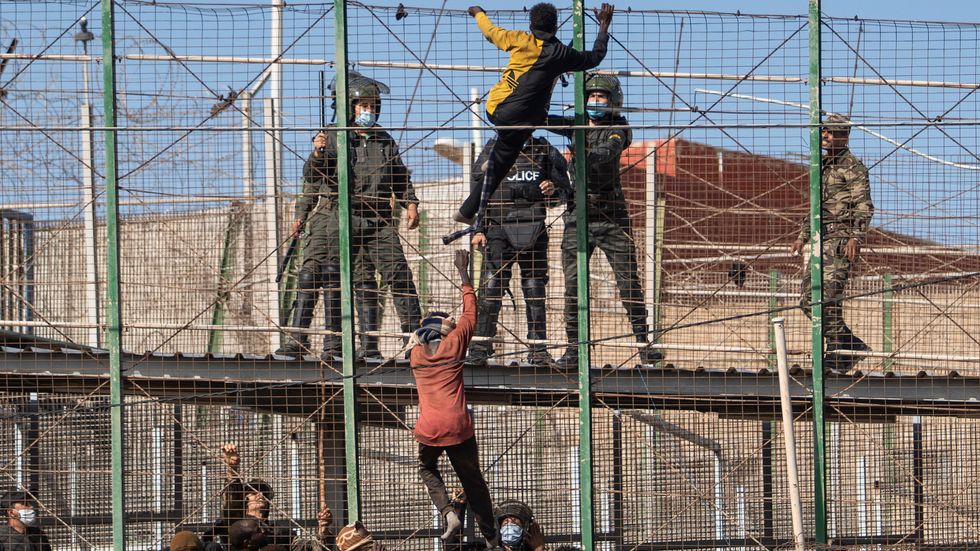 Migranter försöker klättra över stängslet till den spanska exklaven Melilla. Minst 18 dog i trängseln.