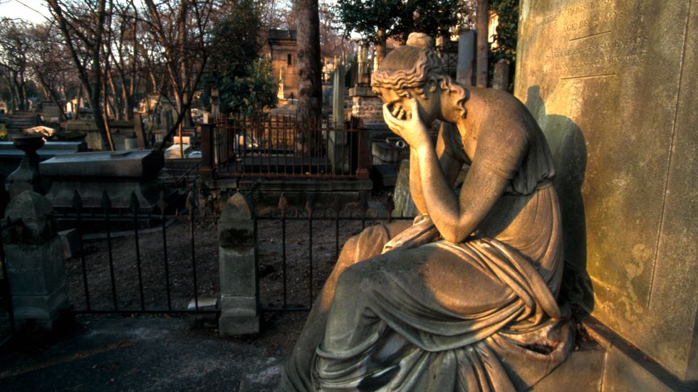 En kvinnoskulptur gråter vid en grav på Père Lachaise-kyrkogården i Paris.