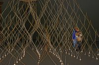 Kengo Kumas installation med tunna slanor av bambu som växer upp ur ljusa hål i golvet.