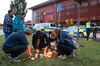 Personer tänder ljus och lägger ned blommor utanför skolan Kronan i Trollhättan.