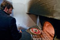 Italiens kulturminister Dario Franceschini firar att "pizzaiuolo" kommit med på Unescos världsarvslista med att grädda en klassisk pizza i den stenugn där den allra första margheritan bakades 1889.