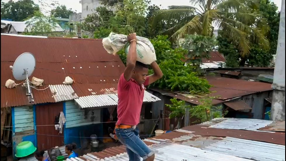 En man förstärker taket med sandsäckar i väntan på cyklonen Batsirai, som drog in över Madagaskar på lördagskvällen.