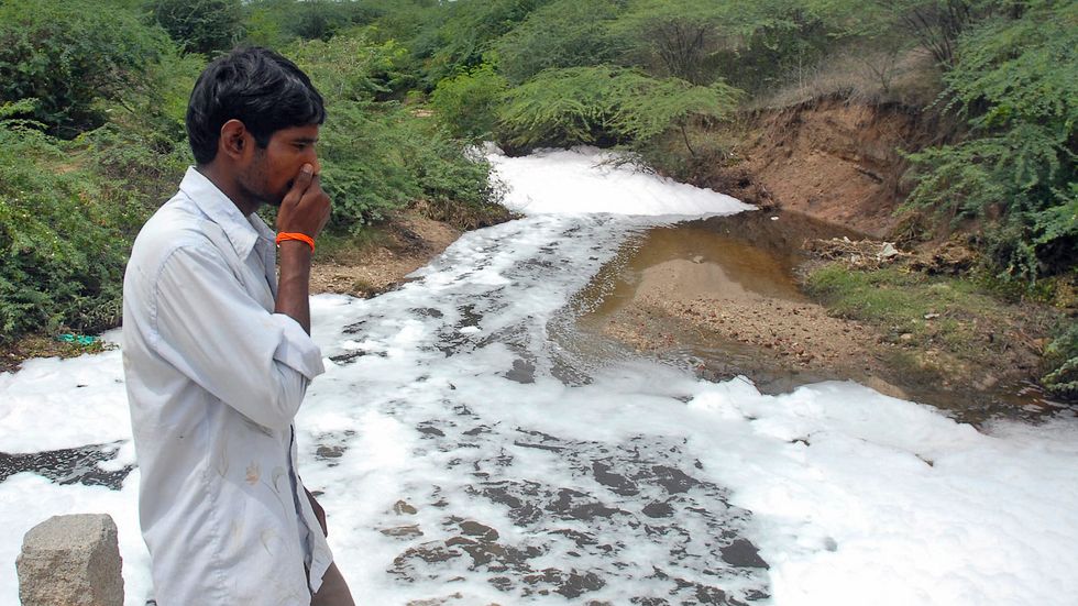 En man i Patancheru håller för näsan av stanken från föroreningarna i floden  Iska Vagu.